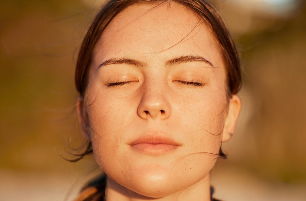 Face, relax and peace with a woman outdoor in nature, standing alone for zen, calm or serenity. Min